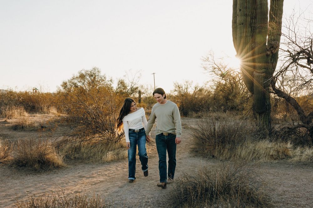A couple frollicks down a dirt path in the desert of Mesa Arizona.