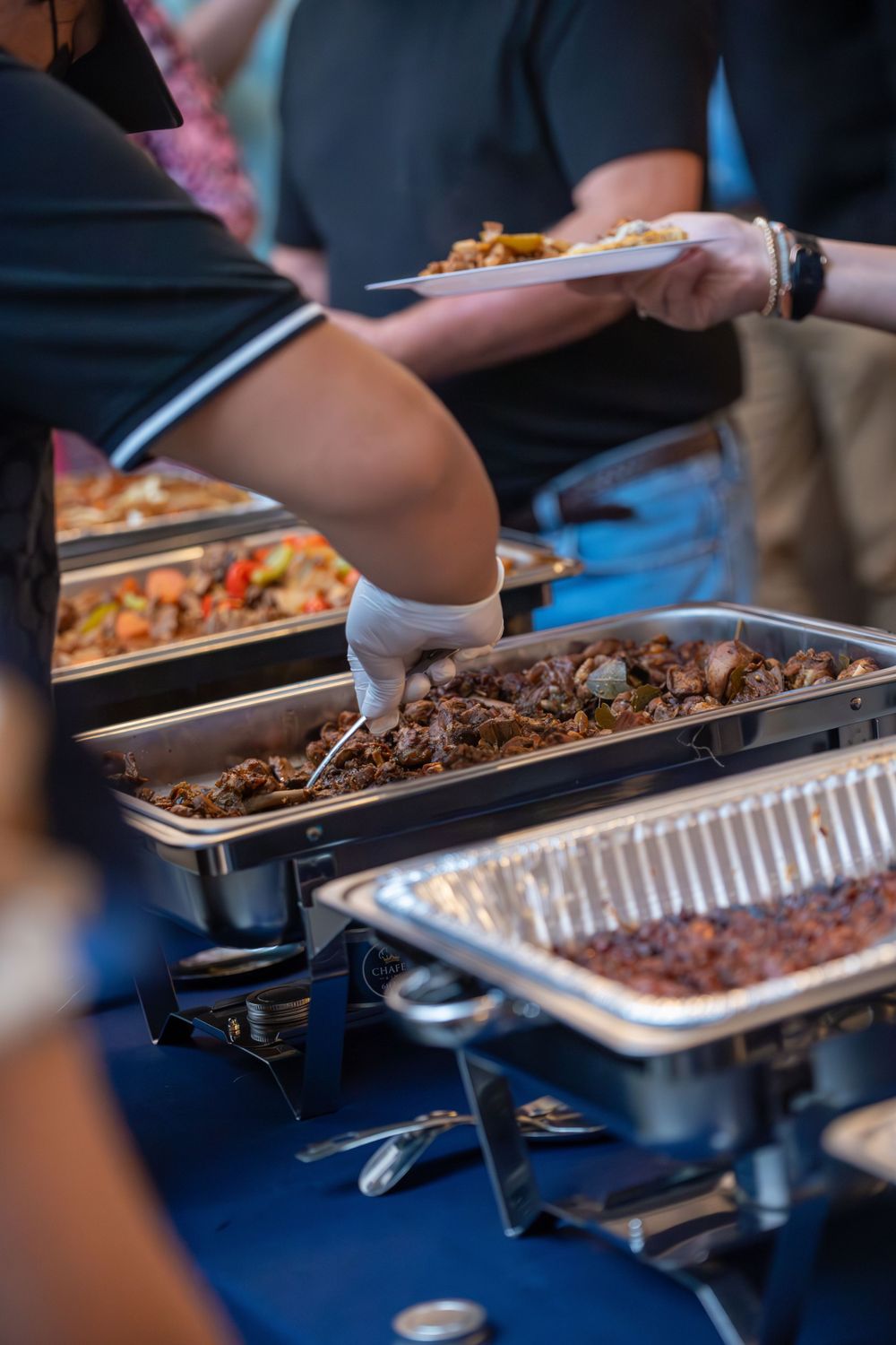Close-up of catering trays filled with various cooked foods being served.