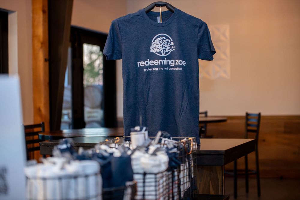 Navy blue t-shirts with logos displayed on hangers at an event.