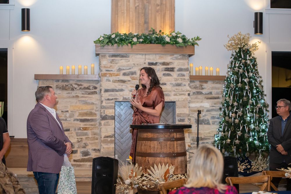 Event space featuring stone walls, barrel decor, and Christmas decorations with guests seated at tables.