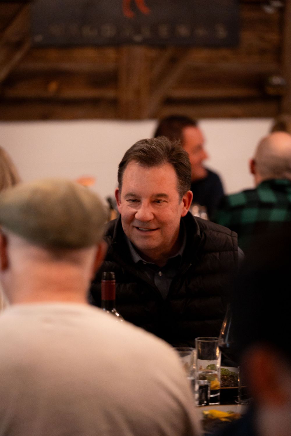 Guests enjoying conversation and drinks at a dimly lit social gathering.