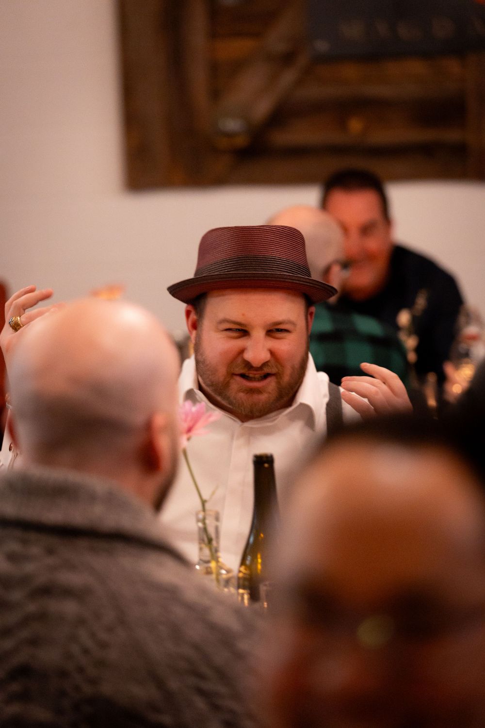 A festive dinner party scene with guests laughing and socializing around a table.