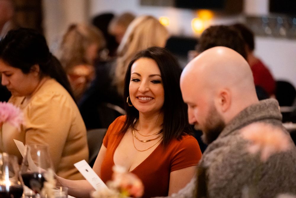 Guests sharing a moment at an elegant dinner party with warm lighting and table settings.