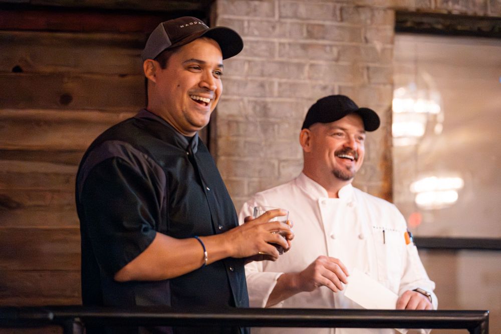 Two people sharing a laugh during a social gathering in a rustic venue.