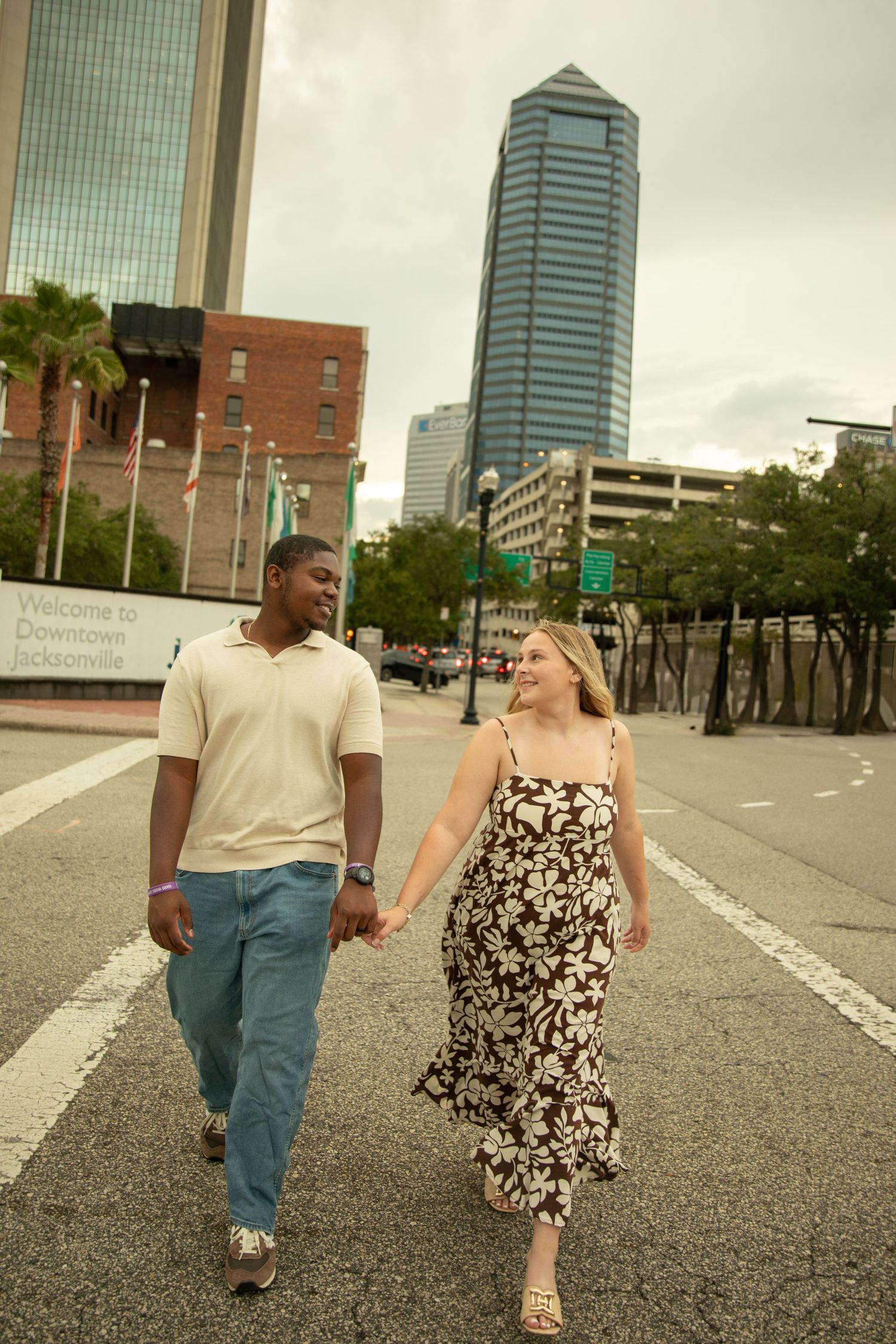 Urban photoshoot with couple walking through city streets with modern buildings in background.