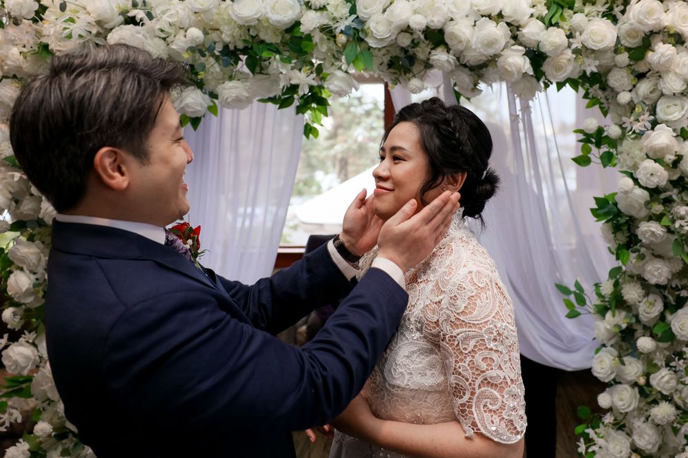 A tender wedding moment under a floral arch with white roses and greenery decorations. smilein wedding photography