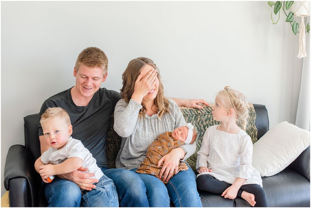 A candid family moment shared on a gray couch in a bright living room.
