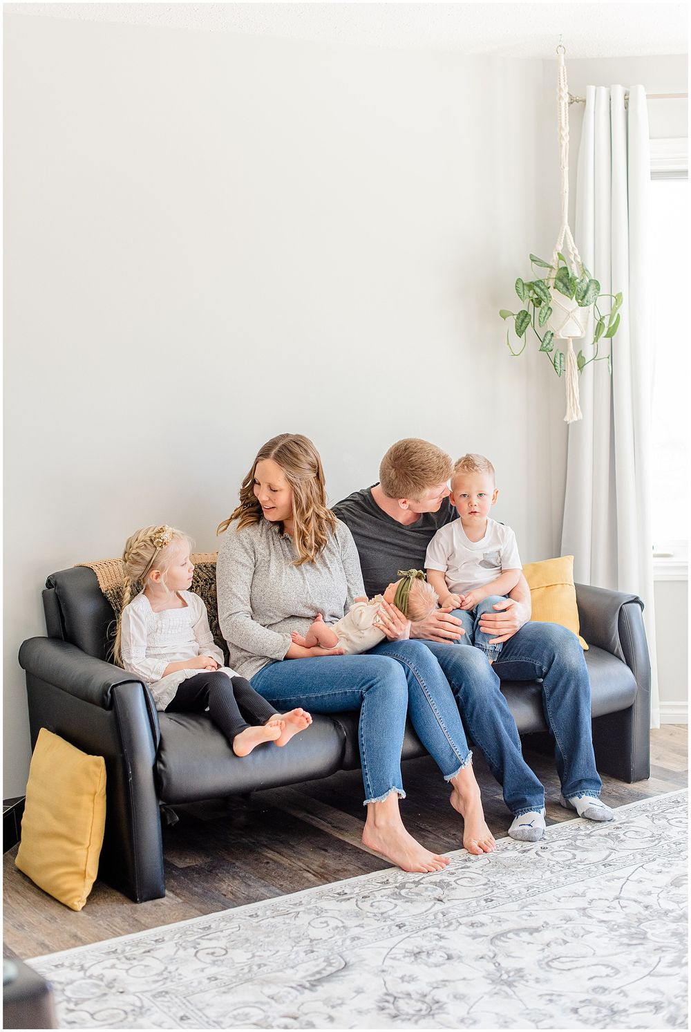 Family relaxing together on a dark gray couch in a bright minimalist living room.