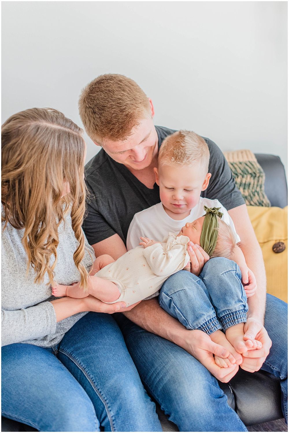 Intimate family moment together on a gray couch during an indoor photography session.
