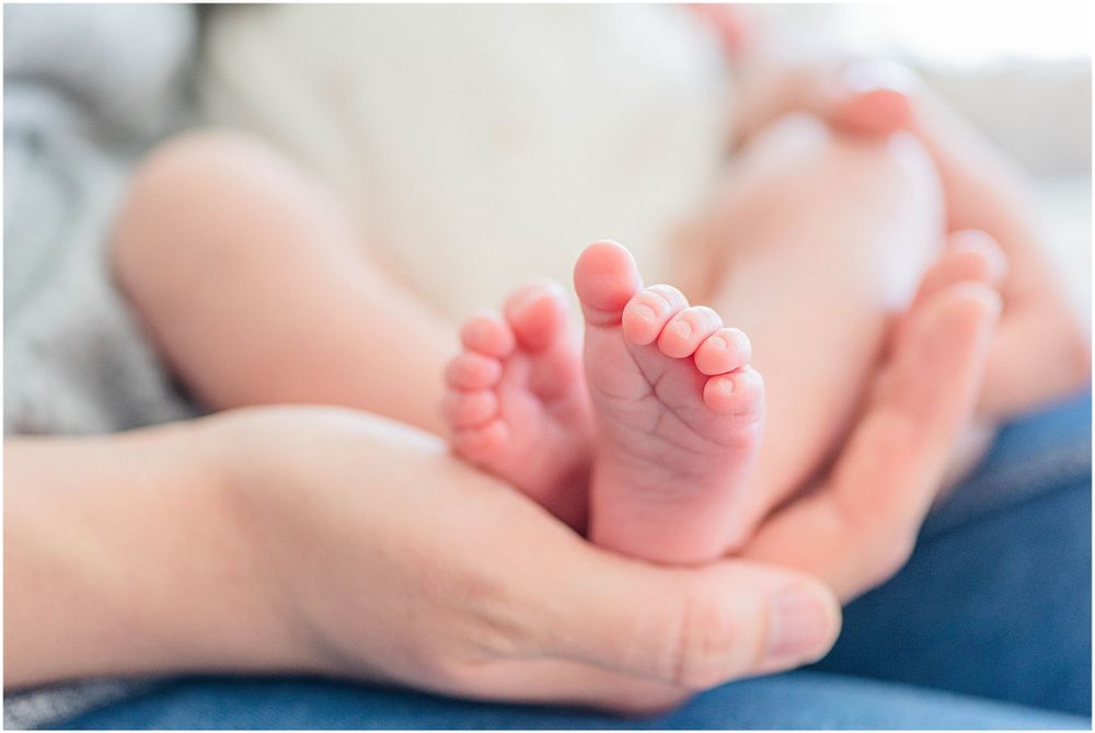 Close up of tiny newborn baby feet being gently held in adult hands.