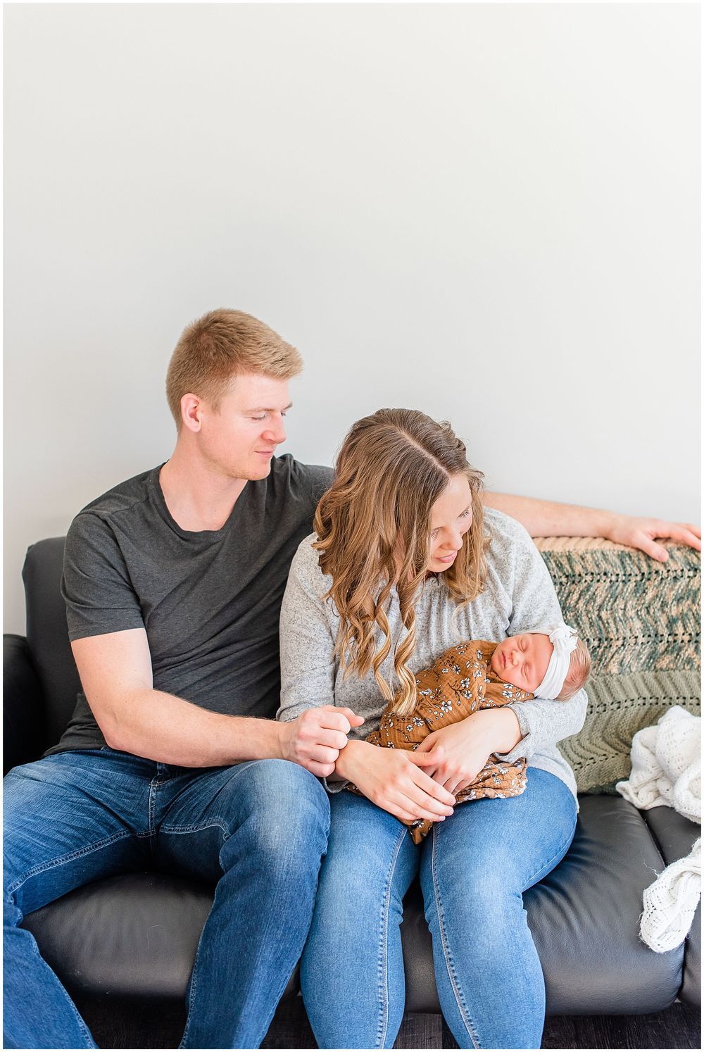 Candid lifestyle photo of parents with newborn on a couch during an indoor session.
