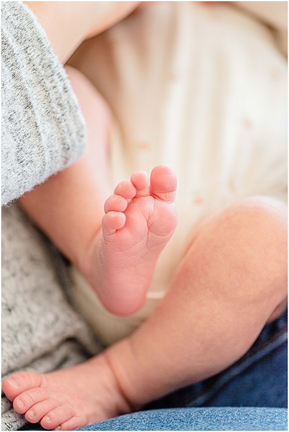 Close-up photo of tiny newborn baby foot against soft fabric background.
