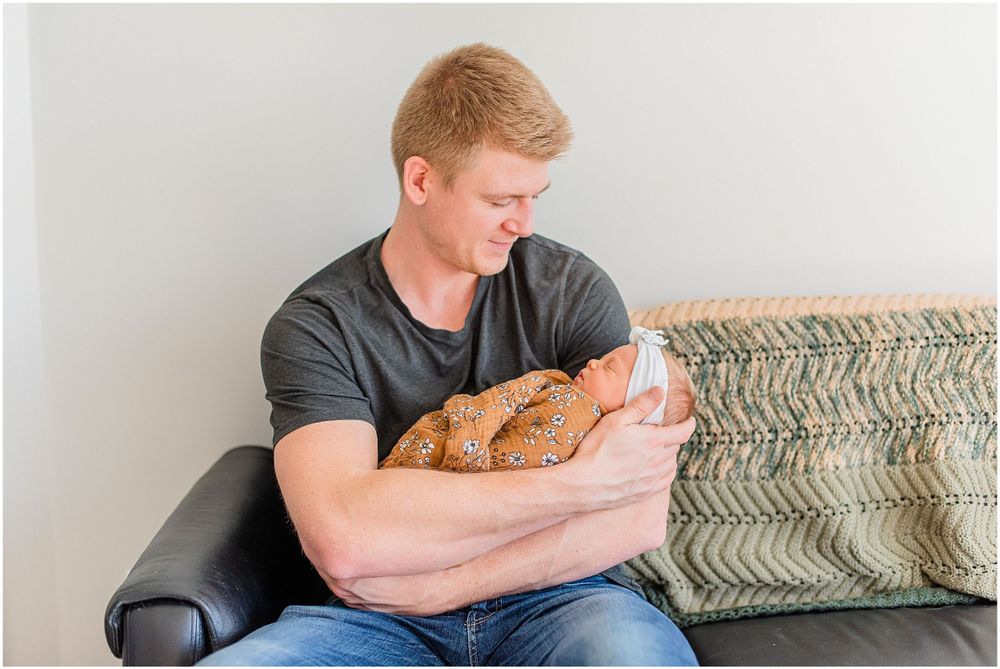 Person in dark shirt holding infant while sitting on textured couch.