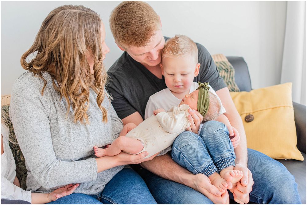 A family sits together on a couch during an intimate lifestyle photography session.