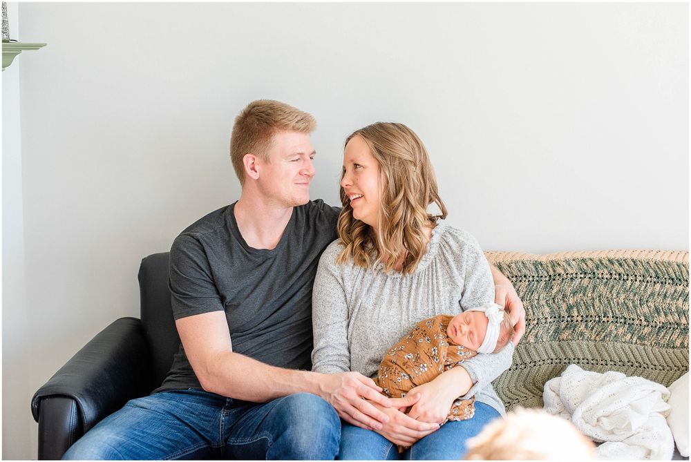 A cozy family portrait on a gray couch in a bright, modern living room.