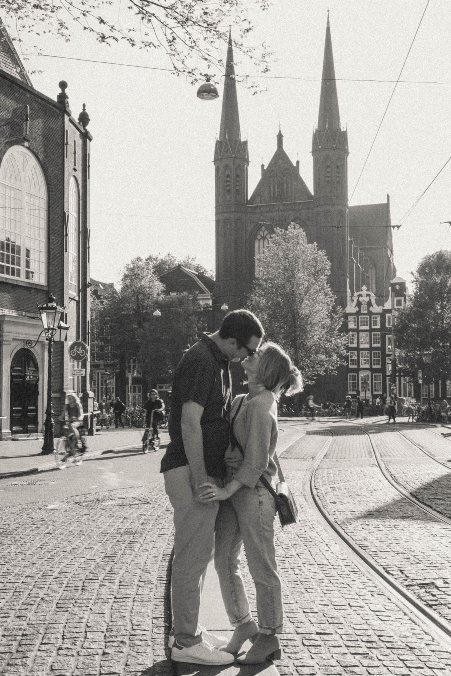 Black and white couple kissing in famous Amsterdam square . Church on a background.