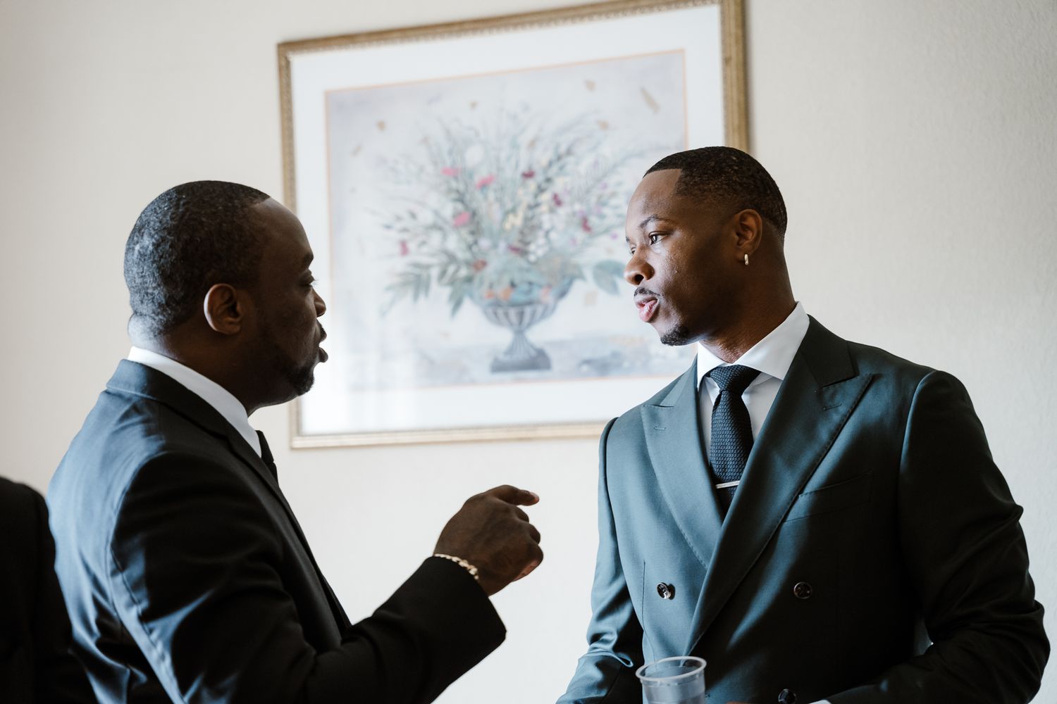 Two people in suits engaged in animated conversation indoors.
