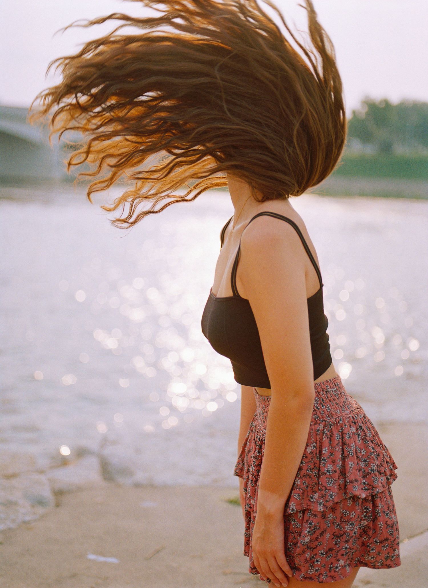 Dynamic motion shot of flowing hair against sparkling water at sunset.