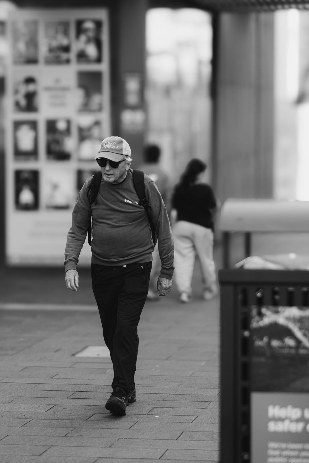 A person walks along a city sidewalk in black and white.