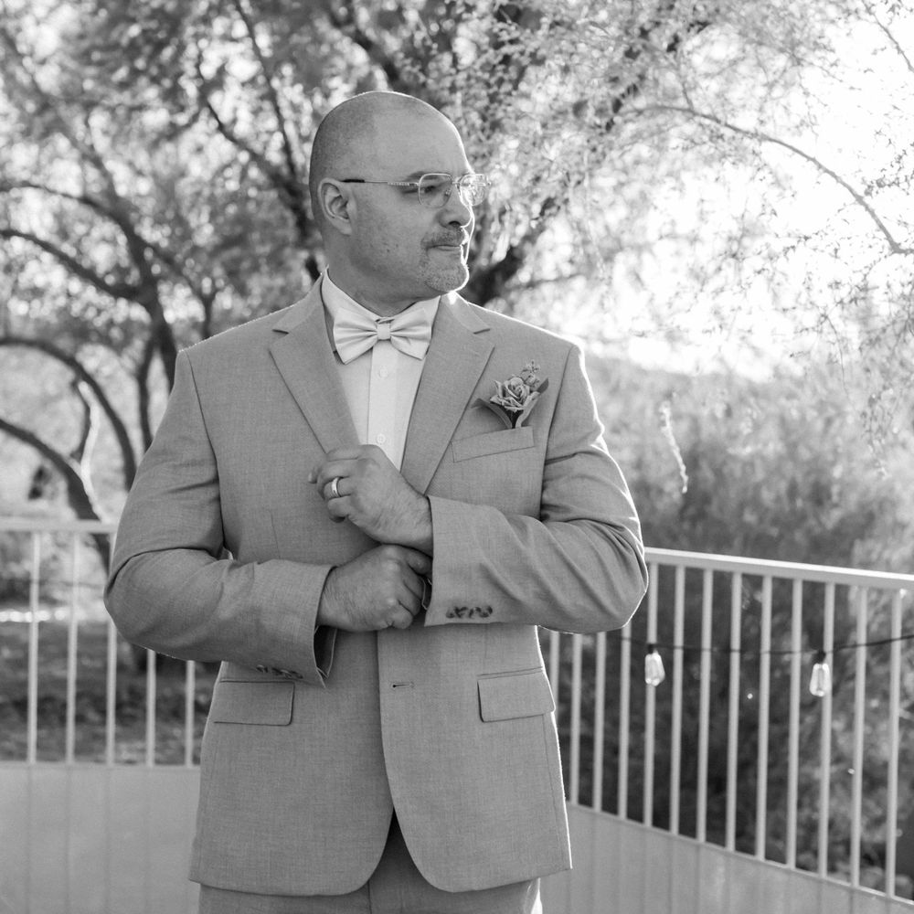 Black and white portrait of a groom in a light gray suit and bowtie.