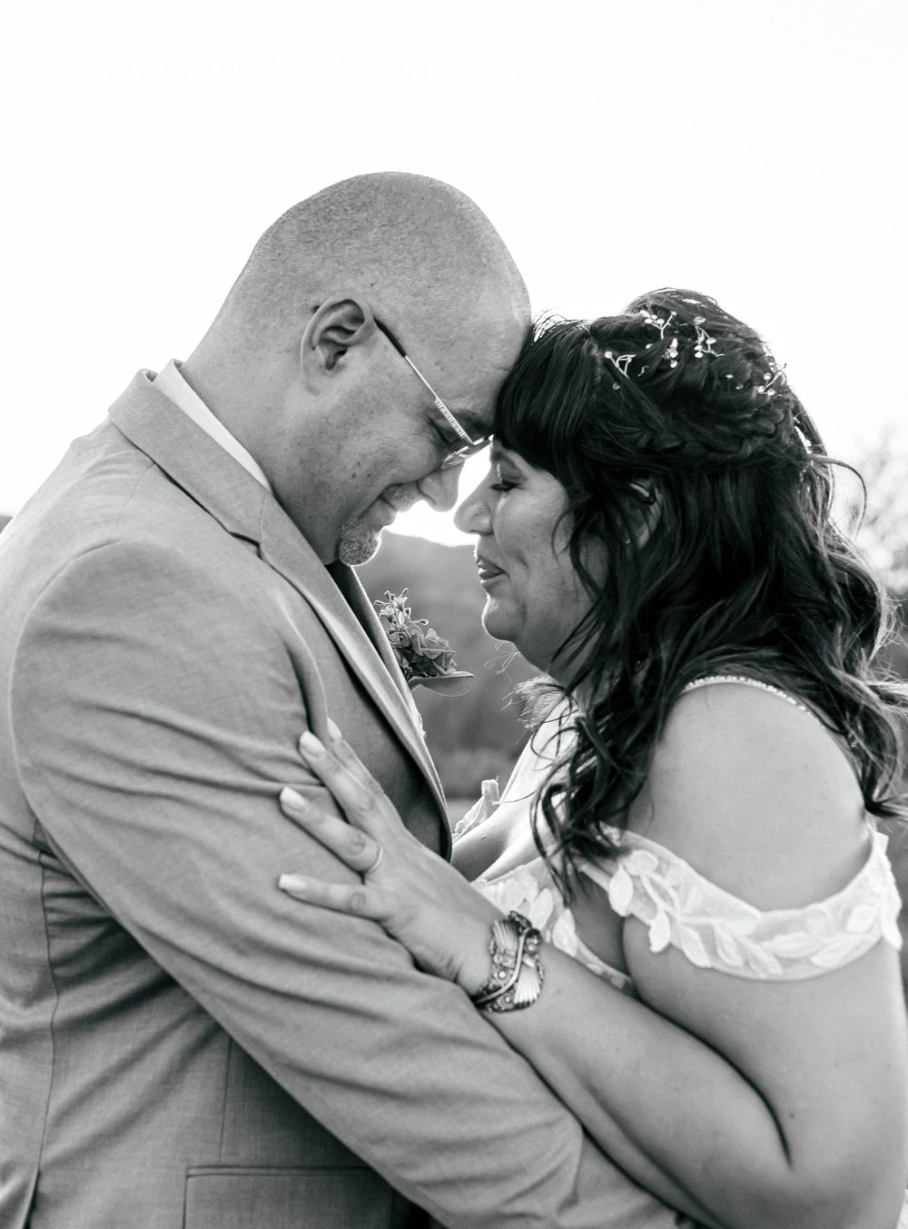 Intimate black and white portrait of a couple in wedding attire sharing a tender moment.