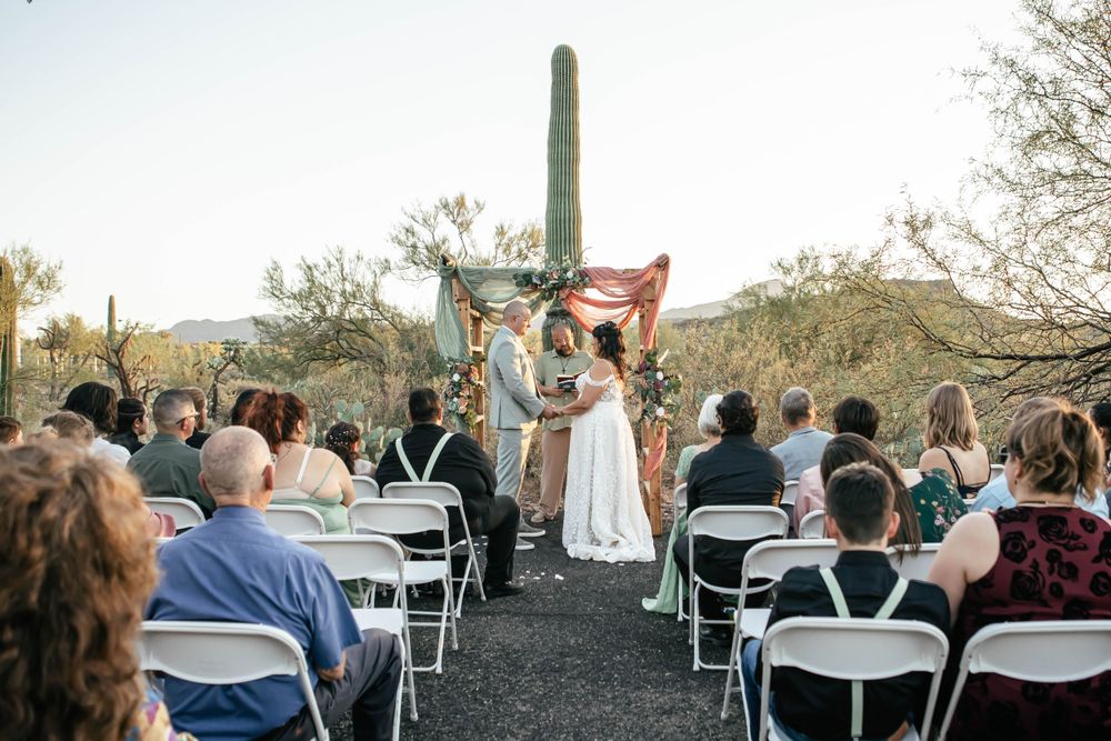 Wedding ceremony setup with white chairs and desert landscape backdrop during golden hour.