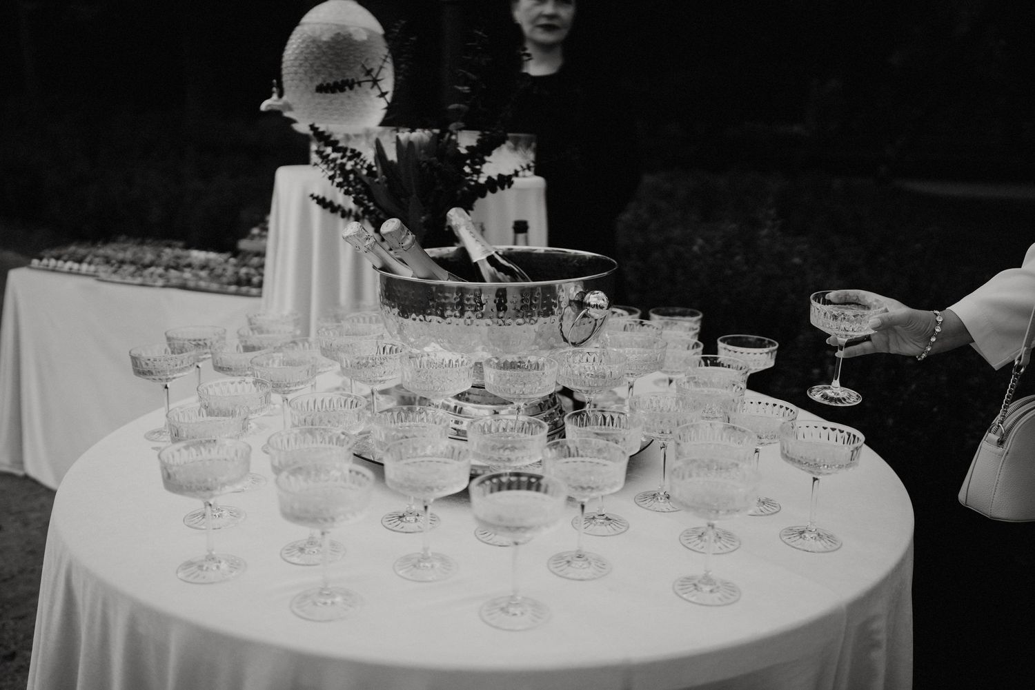 Black and white photo of champagne glasses arranged on an elegant round table at a reception.