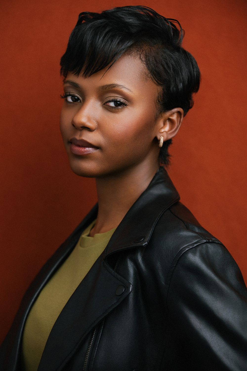 Cinematic African American (black) actor headshot photographed in studio with subtle lighting and a textured red backdrop.