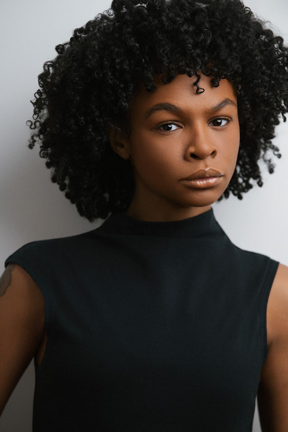 Cinematic African American (black) actor headshot photographed in studio with subtle lighting and a textured color backdrop.