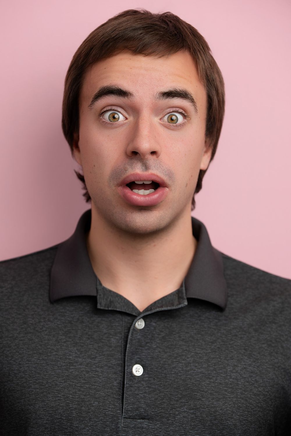 Studio headshot of an actor against a pink colored background, designed for theatrical and comedic on-camera casting submissions.