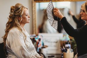 Wedding preparation scene with styling tools and elegant fan being used.