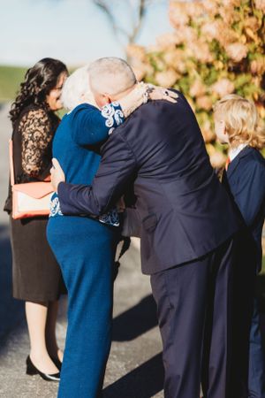 A group embrace during what appears to be a wedding ceremony outdoors.