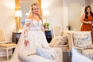 Bride in lace wedding gown with long sleeves in elegant getting ready room.