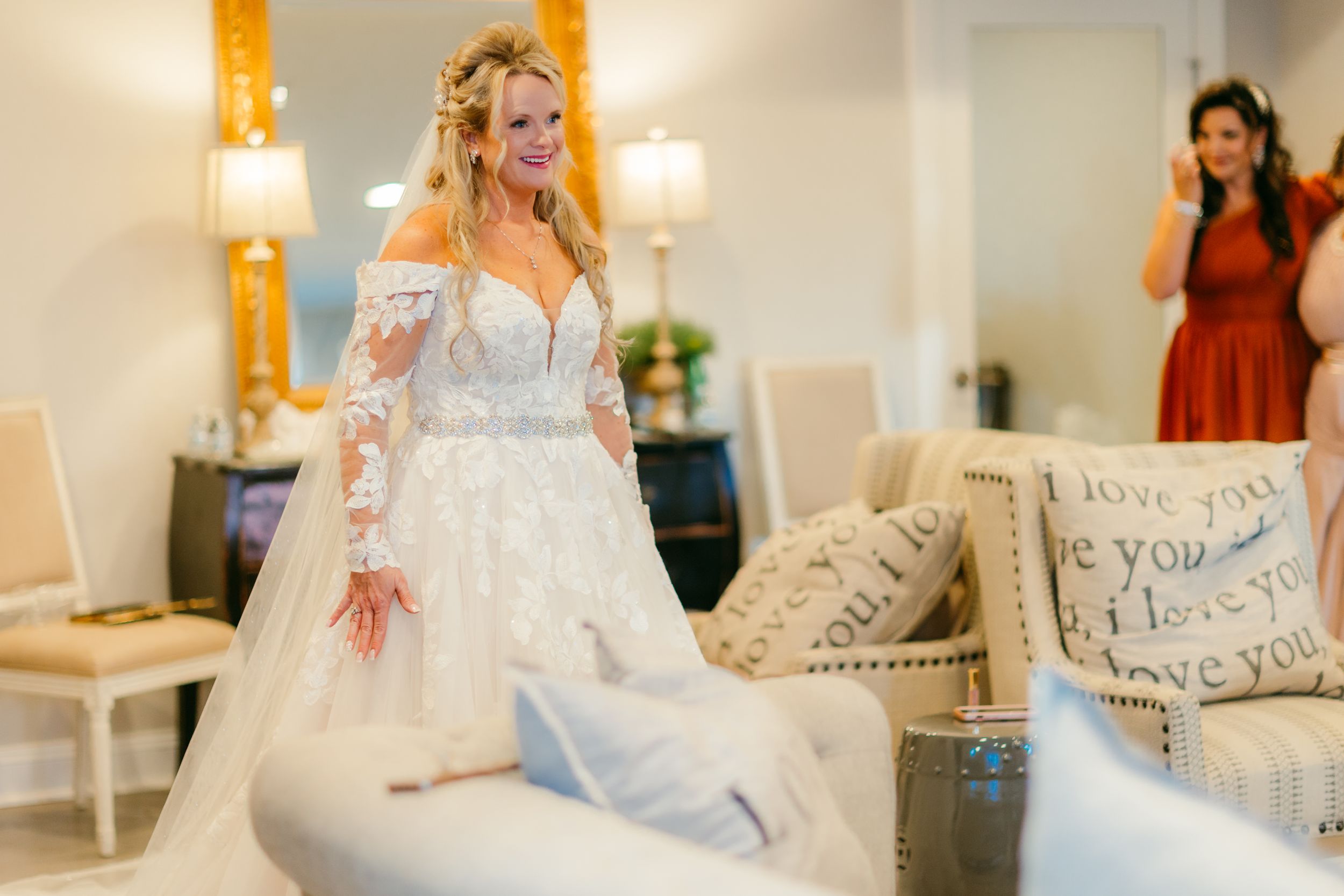 A bride in a beautiful lace wedding gown with long sleeves twirls in an elegant room.