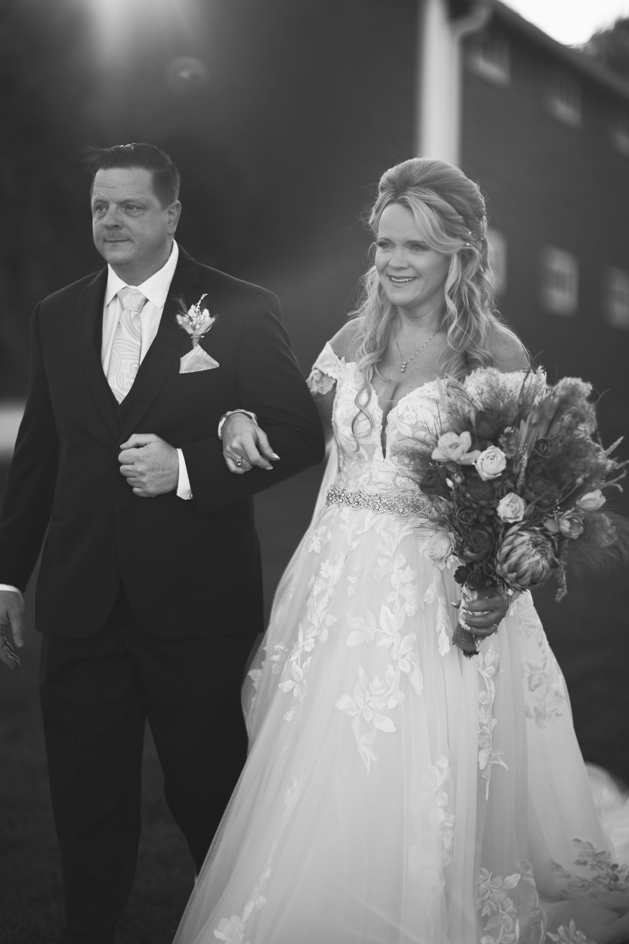 Black and white wedding photo of couple during ceremony with bride holding bouquet.