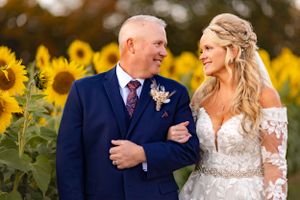 Wedding couple shares joyful moment in front of sunflower garden during golden hour.