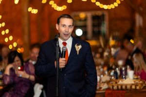 A person giving a wedding speech at an elegant reception with warm lighting and bokeh in the background.