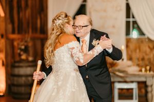 A couple dances together in a rustic barn setting with romantic lighting.