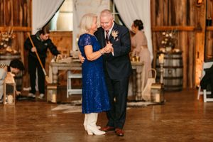 Couples dancing on a wooden floor at a rustic barn wedding reception.