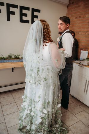 Wedding couple in a rustic kitchen space with exposed brick walls and coffee signage.