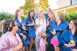 A celebratory group in navy blue robes gather outdoors sharing drinks at a festive event.
