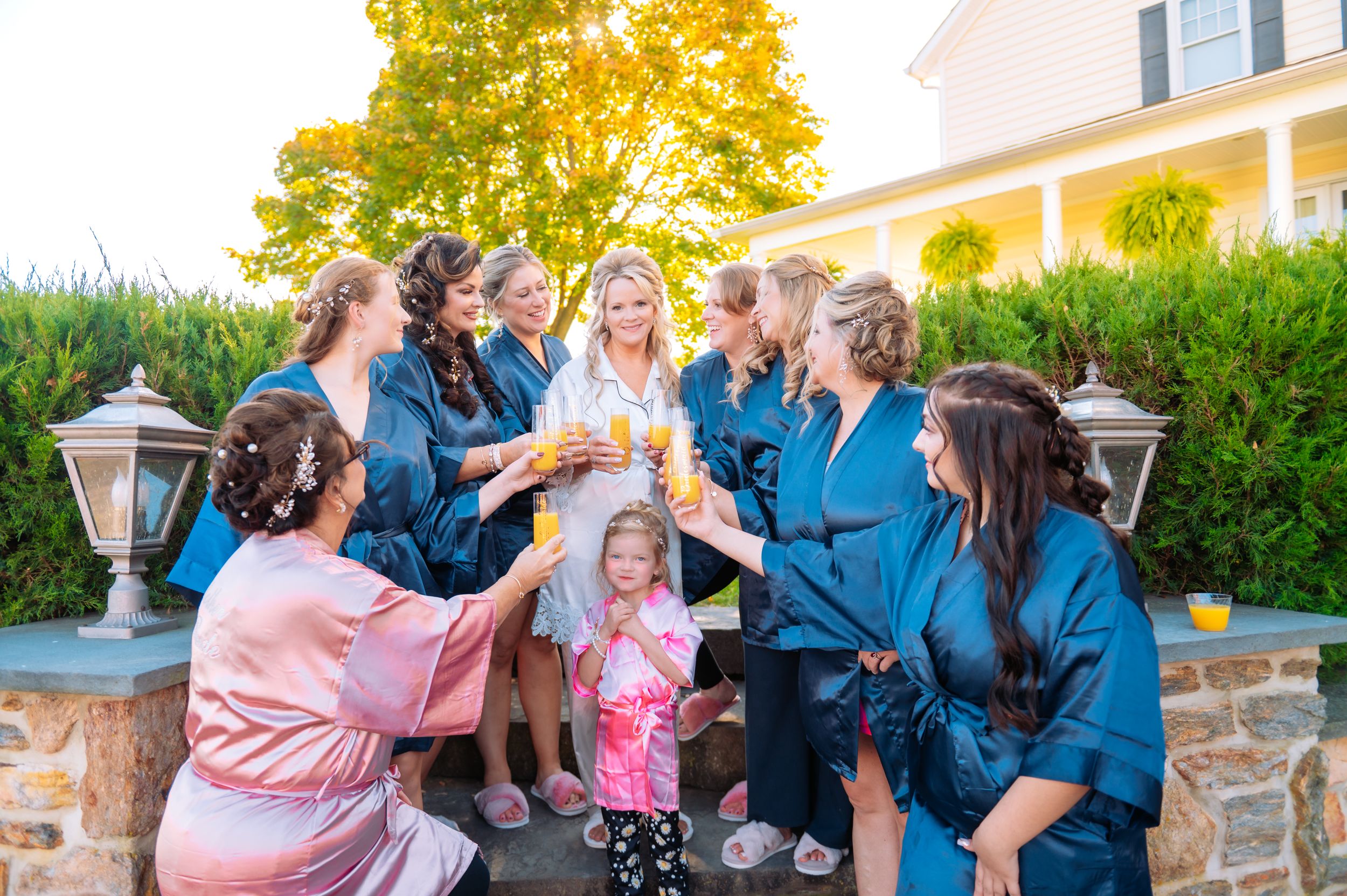 A group in matching blue robes toasting together on a stone patio at sunset.