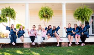 A group in coordinated navy and white outfits sitting together on a white porch with hanging ferns.