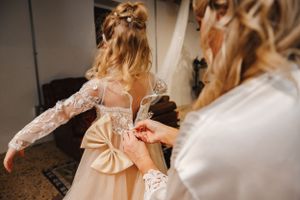 Close-up of intricate lace details being fastened on a wedding gown.