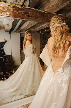 Wedding dress reflection in a rustic room with exposed wooden beams and vintage mirror.