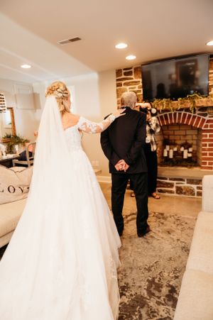 Elegant bride in lace gown sharing a moment in front of a stone fireplace.