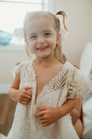Young child wearing delicate lace dress smiles while playing.