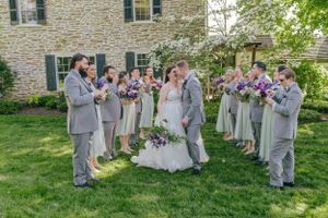 Wedding party gathered on lawn in gray attire during outdoor ceremony.