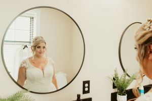 Wedding preparation scene reflected in round mirror showing bridal details.