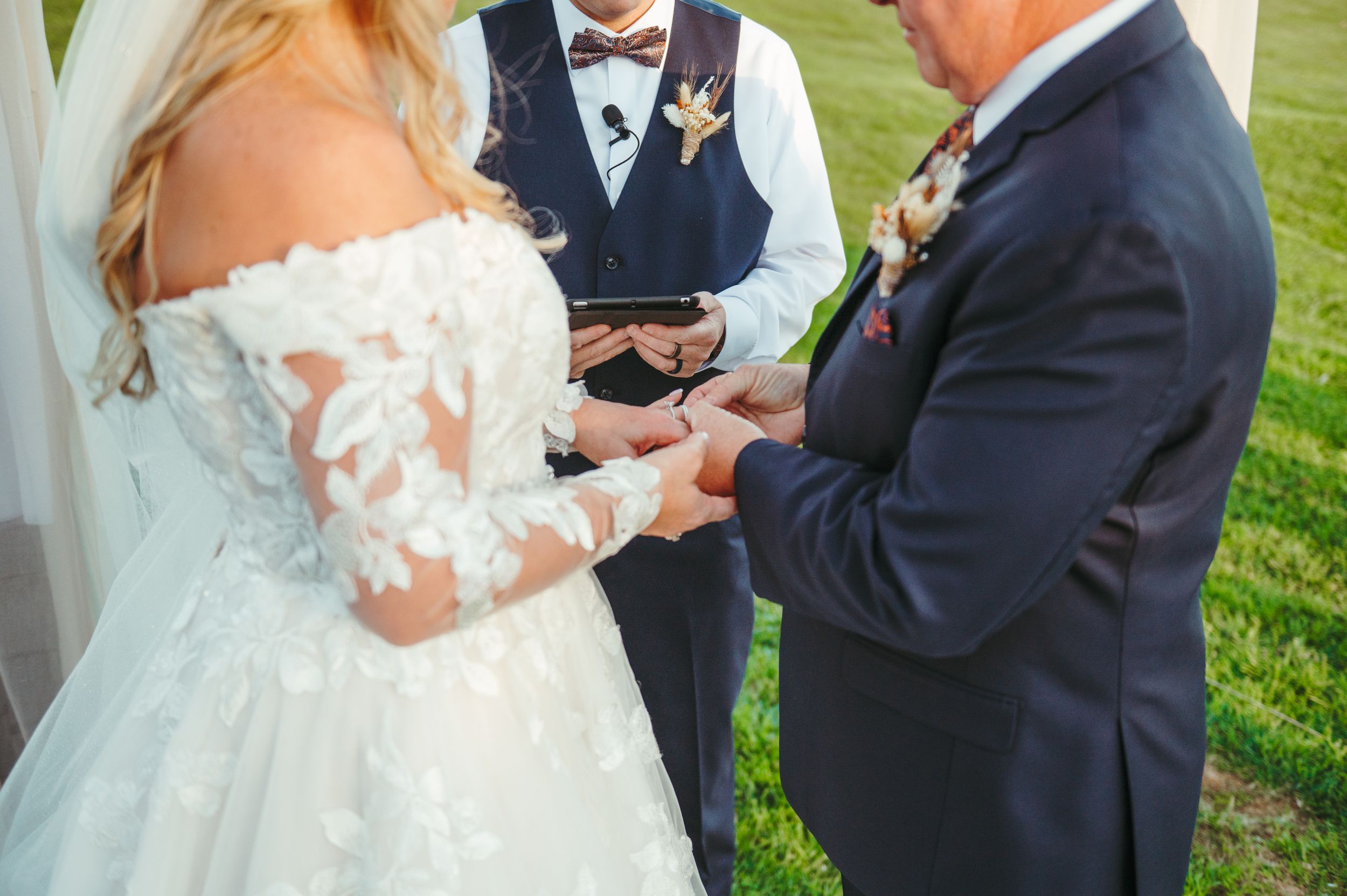 Close-up of ring exchange during outdoor wedding ceremony.